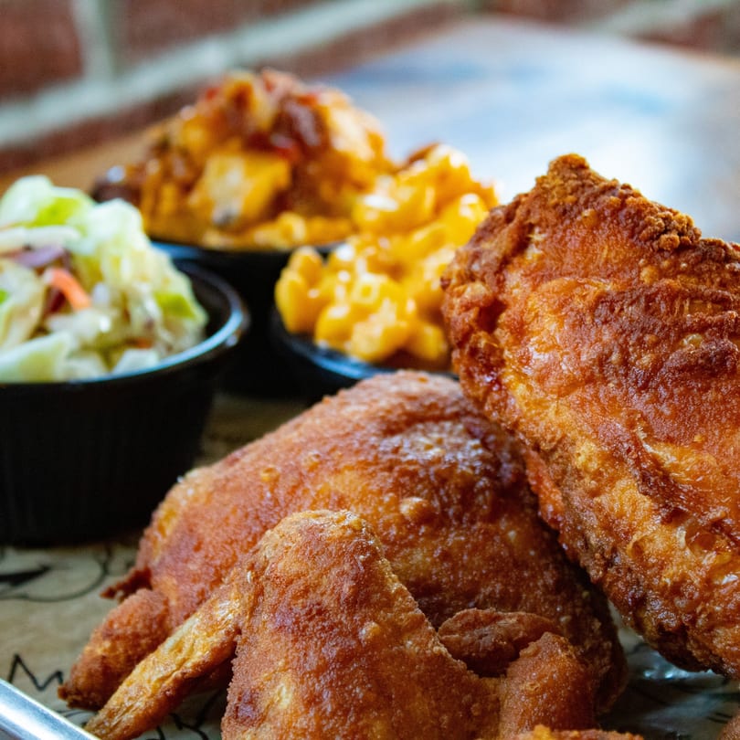 Crispy fried chicken pieces with sides of creamy coleslaw and macaroni and cheese.